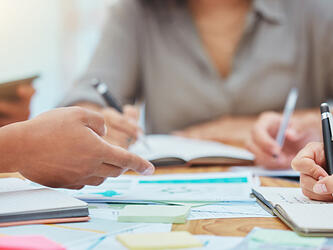 people working together and taking notes and reviewing documents